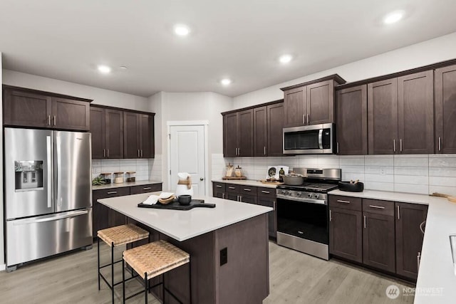 768 SE 11th Pl Lot 05, North Bend, WA 98045 - kitchen with stainless steel appliances, light wood-type flooring, dark brown cabinetry, a kitchen breakfast bar, and backsplash