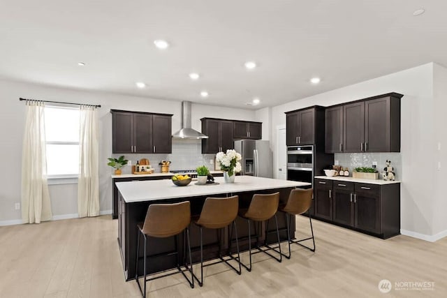 716 SE 11th Pl Unit 7, North Bend, WA 98045 - kitchen featuring appliances with stainless steel finishes, wall chimney exhaust hood, light countertops, backsplash, and light wood finished floors
