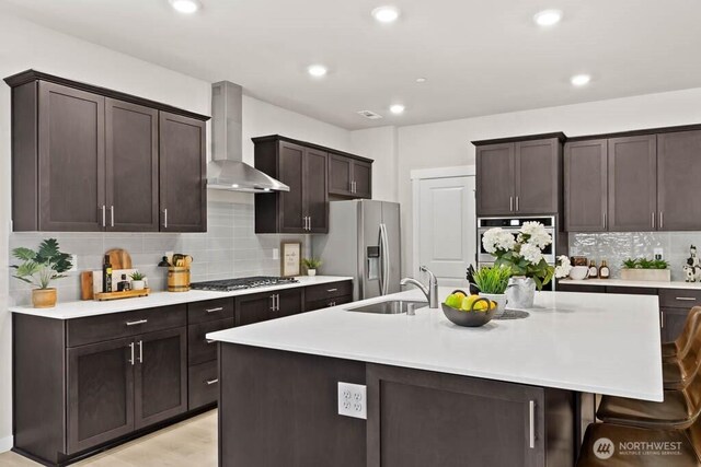 716 SE 11th Pl Unit 7, North Bend, WA 98045 - kitchen featuring wall chimney exhaust hood, appliances with stainless steel finishes, a sink, light countertops, and a center island with sink