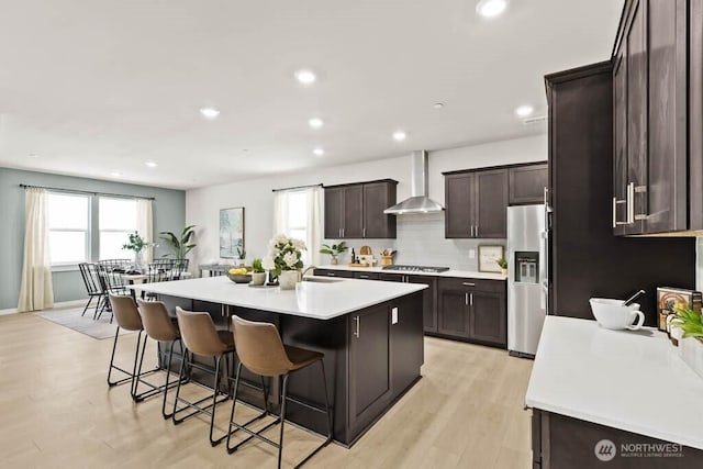 716 SE 11th Pl Unit 7, North Bend, WA 98045 - kitchen featuring wall chimney exhaust hood, appliances with stainless steel finishes, a kitchen breakfast bar, an island with sink, and dark brown cabinets