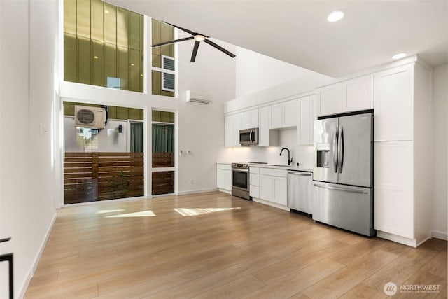 6320 41st Ave SW Unit D, Seattle, WA 98136 - kitchen with appliances with stainless steel finishes, a wall mounted AC, a ceiling fan, white cabinets, and baseboards