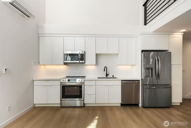 6320 41st Ave SW Unit D, Seattle, WA 98136 - kitchen with stainless steel appliances, a sink, a wall mounted AC, wood finished floors, and decorative backsplash