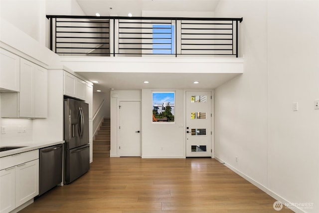 6320 41st Ave SW Unit D, Seattle, WA 98136 - kitchen featuring fridge with ice dispenser, dishwasher, white cabinetry, light wood-type flooring, and baseboards