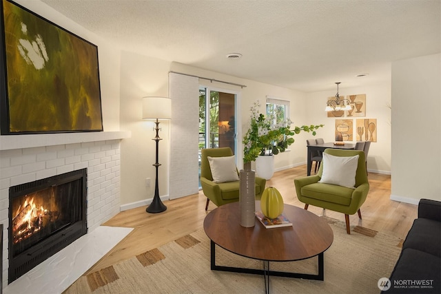 12223 NE Bel-Red Rd Unit D105, Bellevue, WA 98005 - living room featuring light wood-type flooring, a brick fireplace, a chandelier, and baseboards