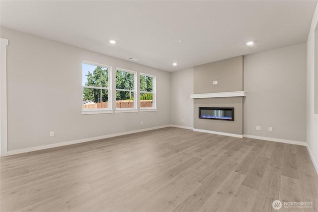 3822 98th Avenue Ct E Unit 9, Edgewood, WA 98371 - unfurnished living room featuring light wood-style flooring, a glass covered fireplace, and recessed lighting