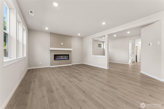 3822 98th Avenue Ct E Unit 9, Edgewood, WA 98371 - unfurnished living room with healthy amount of natural light, light wood finished floors, recessed lighting, and a glass covered fireplace