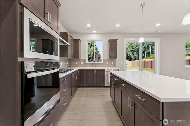 3822 98th Avenue Ct E Unit 9, Edgewood, WA 98371 - kitchen featuring appliances with stainless steel finishes, light wood finished floors, dark brown cabinetry, light countertops, and decorative backsplash