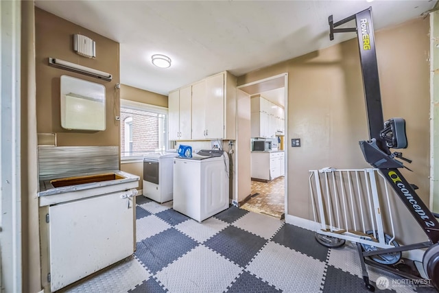 8495 Williams Rd E, Wilbur, WA 99185 - kitchen with washer and dryer, white cabinets, light flooring, and baseboards