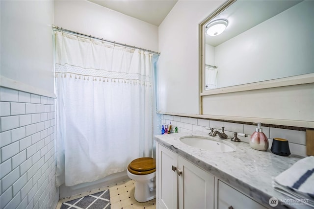 8495 Williams Rd E, Wilbur, WA 99185 - bathroom featuring tile walls, vanity, toilet, tile patterned floors, and shower / tub combo with curtain