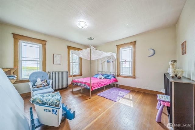 8495 Williams Rd E, Wilbur, WA 99185 - bedroom featuring radiator, multiple windows, wood finished floors, and baseboards