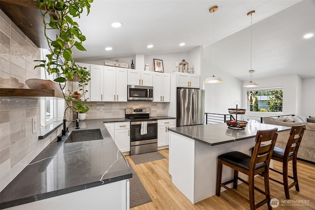 21710 104th Ave E, Graham, WA 98338 - kitchen featuring stainless steel appliances, a sink, lofted ceiling, a breakfast bar, and backsplash