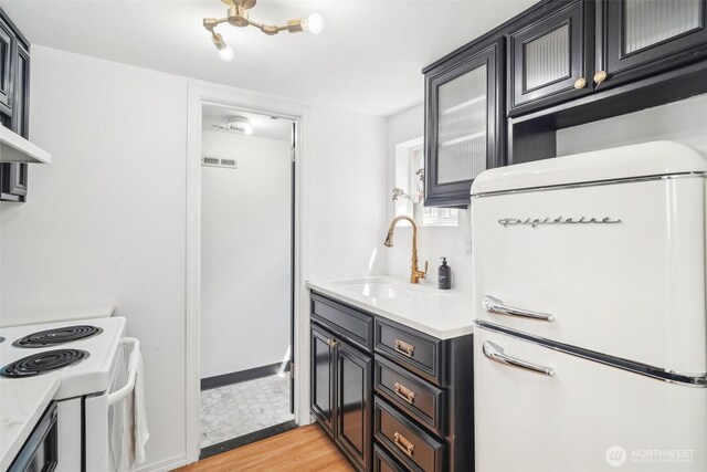 603 NW 52nd St, Seattle, WA 98107 - kitchen featuring white appliances, a sink, light countertops, light wood finished floors, and dark cabinets