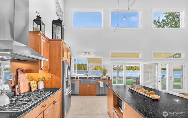 62 E N Bay Rd, Allyn, WA 98524 - kitchen featuring wall chimney range hood, stainless steel appliances, a sink, a towering ceiling, and light tile patterned floors