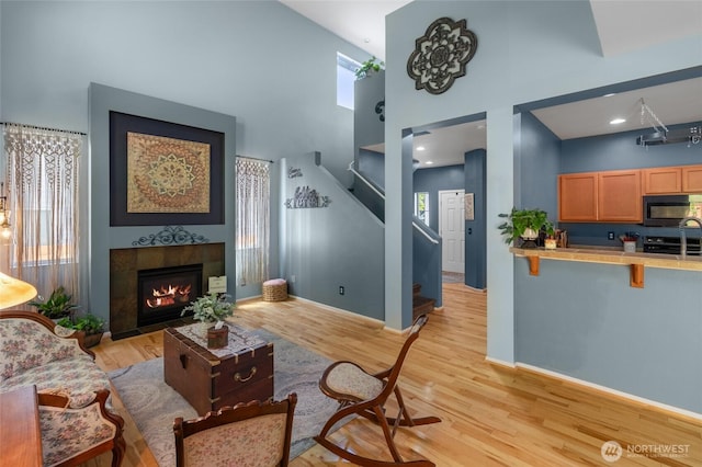 782 Fenway Ln SW, Tumwater, WA 98512 - living area featuring a towering ceiling, stairway, plenty of natural light, light wood-style floors, and baseboards