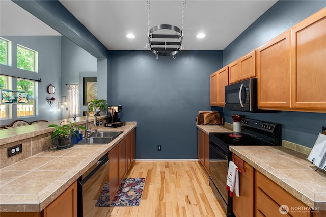 782 Fenway Ln SW, Tumwater, WA 98512 - kitchen with black appliances, a sink, a peninsula, light wood-style flooring, and baseboards