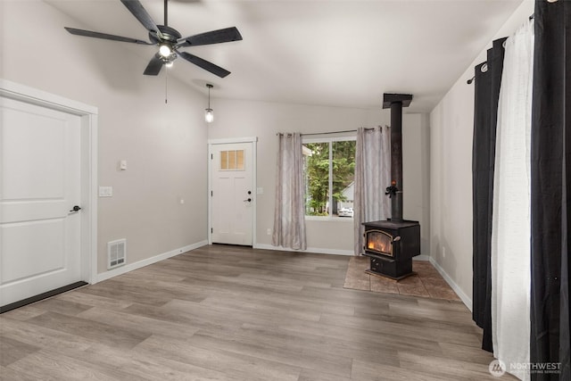 18822 Rampart Dr SE, Yelm, WA 98597 - unfurnished living room featuring a wood stove, vaulted ceiling, ceiling fan, light wood-style floors, and baseboards