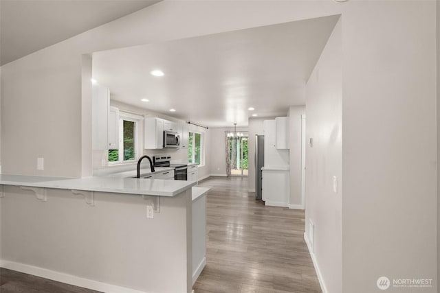 18822 Rampart Dr SE, Yelm, WA 98597 - kitchen with appliances with stainless steel finishes, a kitchen breakfast bar, a peninsula, white cabinetry, and recessed lighting