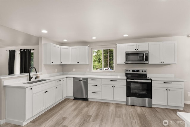 18822 Rampart Dr SE, Yelm, WA 98597 - kitchen with stainless steel appliances, a sink, light wood-style flooring, white cabinetry, and light countertops