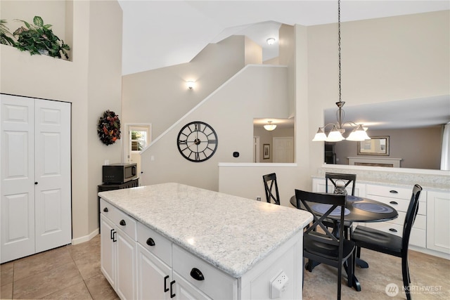 23813 109th Street Ct E, Buckley, WA 98321 - kitchen featuring high vaulted ceiling, stainless steel microwave, a center island, white cabinets, and a chandelier
