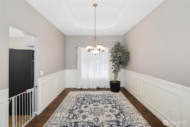 23813 109th Street Ct E, Buckley, WA 98321 - dining space featuring a chandelier, dark wood-style floors, a raised ceiling, a wainscoted wall, and a decorative wall