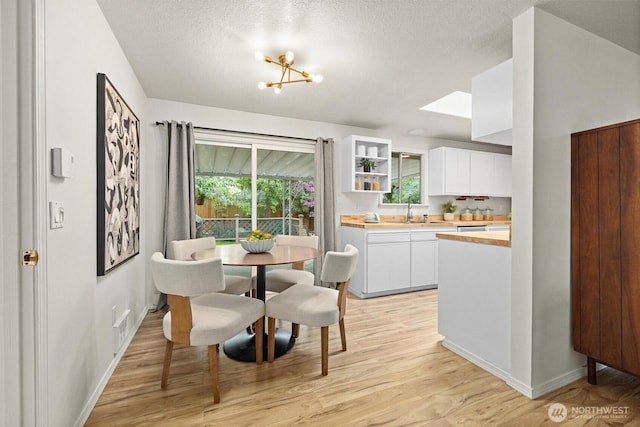 19019 Grannis Rd, Bothell, WA 98012 - dining area with light wood finished floors, baseboards, a textured ceiling, a skylight, and a chandelier