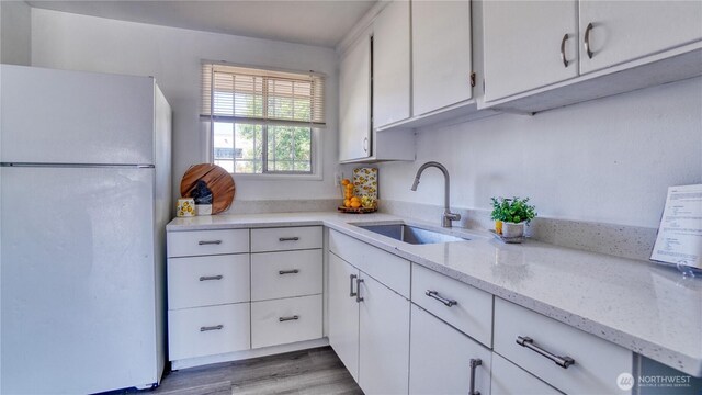 4821 101st St SW, Lakewood, WA 98499 - kitchen with freestanding refrigerator, a sink, white cabinets, light stone countertops, and wood finished floors