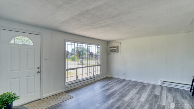 4821 101st St SW, Lakewood, WA 98499 - foyer featuring baseboard heating, wood finished floors, a wall mounted AC, baseboards, and a textured ceiling