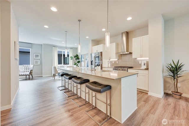2349 N 147th St Unit B, Shoreline, WA 98133 - kitchen featuring wall chimney exhaust hood, stainless steel refrigerator with ice dispenser, light wood-style flooring, an island with sink, and a kitchen bar