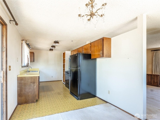 604 N Larch Ave, East Wenatchee, WA 98802 - kitchen featuring freestanding refrigerator, a textured ceiling, brown cabinetry, light countertops, and a sink