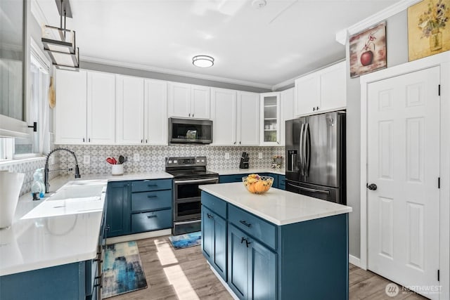 8712 177th St E, Puyallup, WA 98375 - kitchen featuring stainless steel appliances, blue cabinetry, light wood finished floors, light countertops, and backsplash