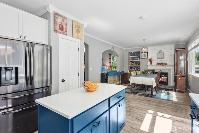 8712 177th St E, Puyallup, WA 98375 - kitchen featuring stainless steel fridge, blue cabinets, ornamental molding, light countertops, and light wood-style flooring
