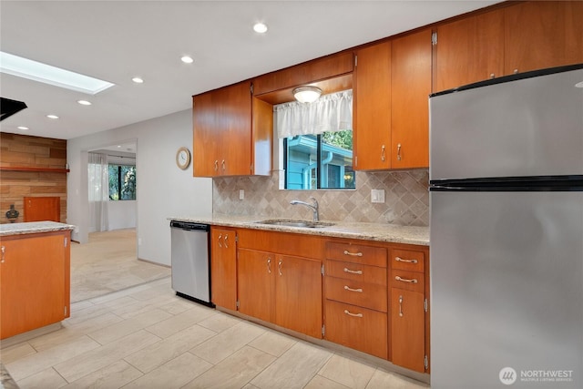 10202 Pipeline Rd E, Puyallup, WA 98373 - kitchen with stainless steel appliances, a sink, decorative backsplash, a skylight, and brown cabinetry