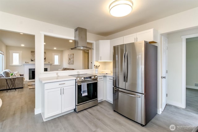2914 S 17th St, Tacoma, WA 98405 - kitchen with appliances with stainless steel finishes, island range hood, light wood-style floors, white cabinets, and light countertops