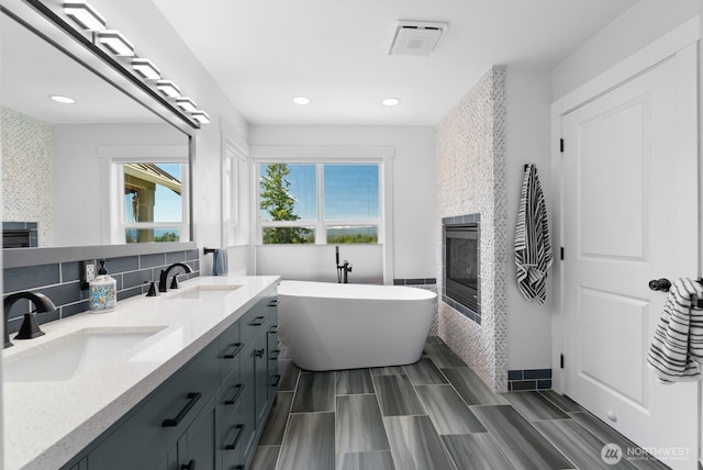 5675 E Hillcrest Dr, Port Orchard, WA 98366 - bathroom with a freestanding tub, double vanity, a large fireplace, recessed lighting, and backsplash