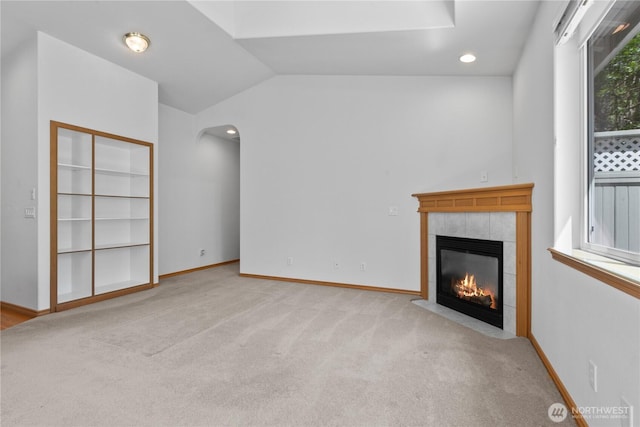 509 Clover Ln, Bellingham, WA 98226 - unfurnished living room featuring a fireplace, carpet floors, lofted ceiling, baseboards, and arched walkways
