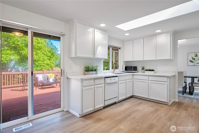 7718 NE 183rd St, Kenmore, WA 98028 - kitchen with dishwasher, stainless steel microwave, a skylight, light wood-style floors, and recessed lighting