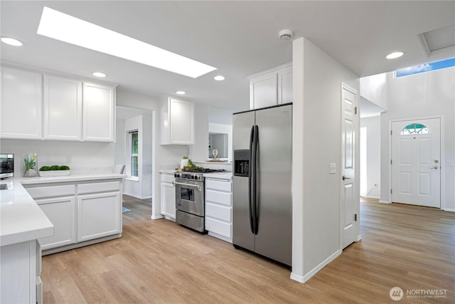 7718 NE 183rd St, Kenmore, WA 98028 - kitchen with stainless steel appliances, a skylight, light wood finished floors, white cabinetry, and recessed lighting
