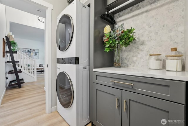 27716 NE 30th St, Redmond, WA 98053 - laundry room featuring stacked washer and clothes dryer, light wood finished floors, cabinet space, and baseboards
