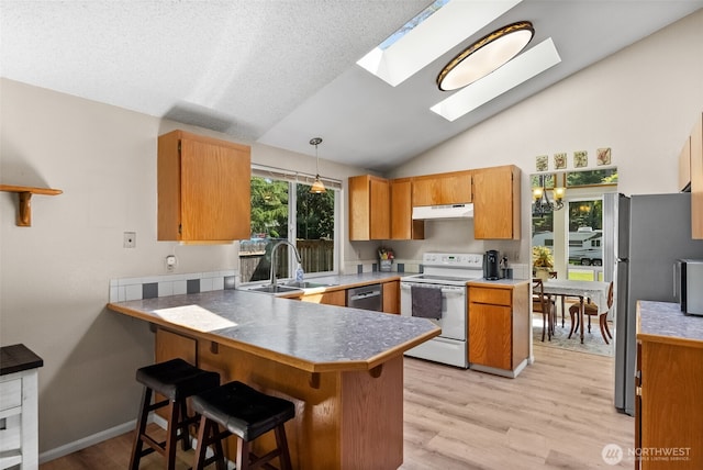 11726 130th Avenue Ct E, Puyallup, WA 98374 - kitchen featuring appliances with stainless steel finishes, a sink, a peninsula, vaulted ceiling, and light wood-style floors