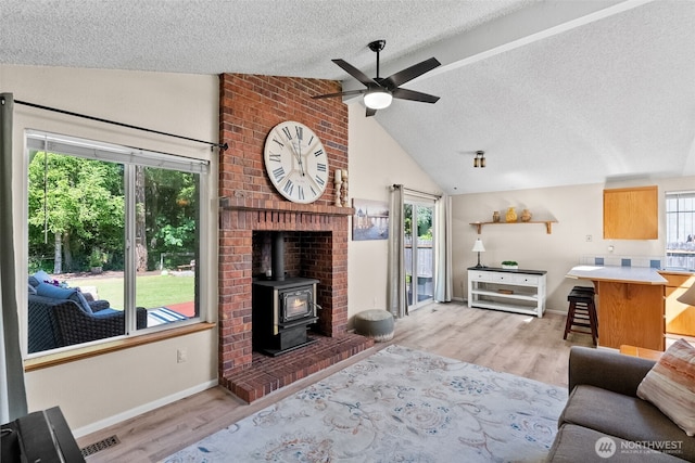 11726 130th Avenue Ct E, Puyallup, WA 98374 - living area with lofted ceiling, a wood stove, a textured ceiling, ceiling fan, and light wood-style floors