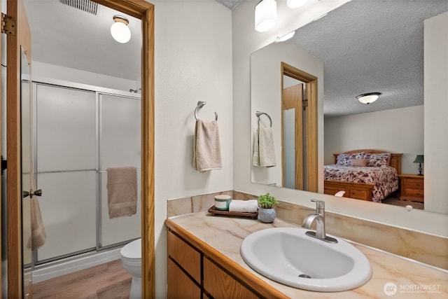 11726 130th Avenue Ct E, Puyallup, WA 98374 - ensuite bathroom featuring toilet, a stall shower, vanity, wood finished floors, and a textured ceiling