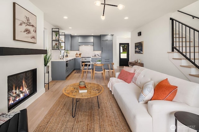 6707 117th Ave NE, Kirkland, WA 98033 - living room with light wood-style floors, stairway, recessed lighting, and a warm lit fireplace