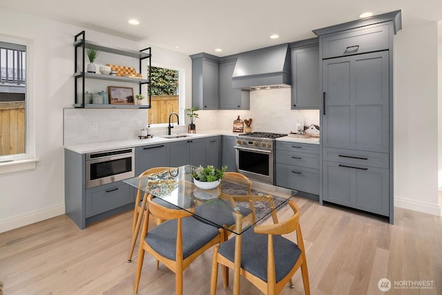 6707 117th Ave NE, Kirkland, WA 98033 - kitchen featuring wall chimney exhaust hood, stainless steel appliances, gray cabinetry, baseboards, and tasteful backsplash