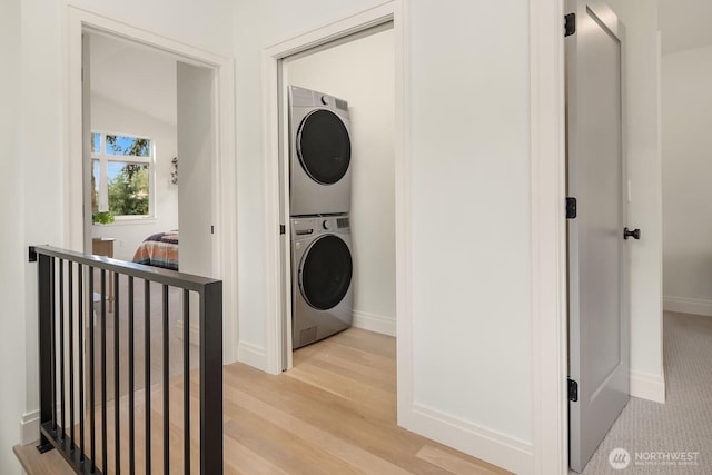 6707 117th Ave NE, Kirkland, WA 98033 - washroom featuring stacked washing machine and dryer, baseboards, and light wood finished floors