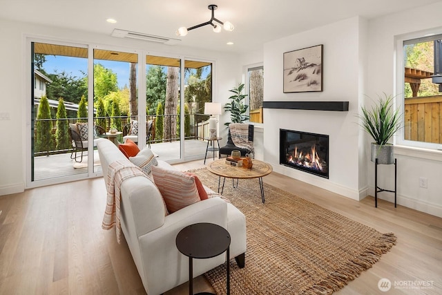6707 117th Ave NE, Kirkland, WA 98033 - living room with healthy amount of natural light, a glass covered fireplace, wood finished floors, baseboards, and recessed lighting