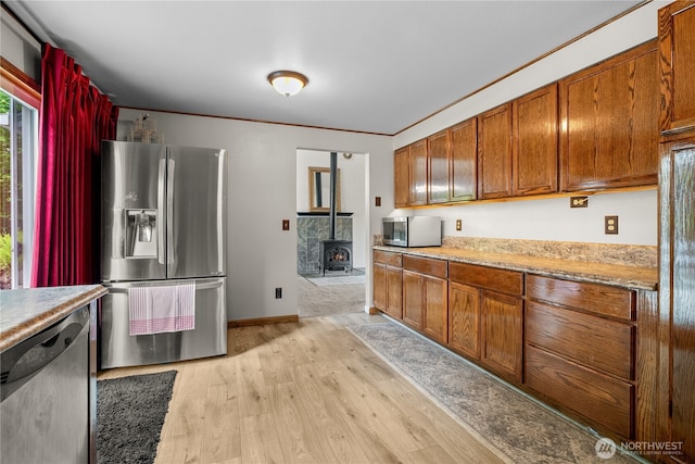 37911 300th Ave SE, Enumclaw, WA 98022 - kitchen featuring appliances with stainless steel finishes, a wood stove, light wood-type flooring, light countertops, and brown cabinets