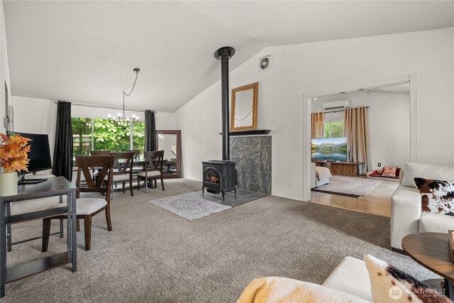 37911 300th Ave SE, Enumclaw, WA 98022 - living room featuring a wall unit AC, a wood stove, lofted ceiling, plenty of natural light, and carpet floors