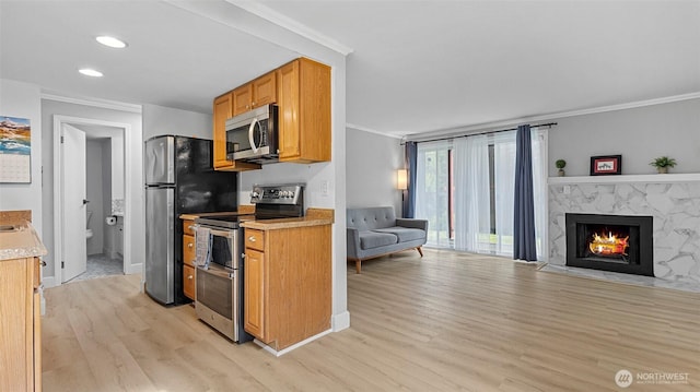 323 128th St SE Unit K120, Everett, WA 98208 - kitchen featuring appliances with stainless steel finishes, ornamental molding, light wood-style floors, open floor plan, and light countertops