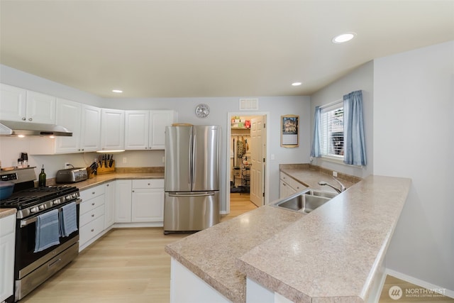 2760 SW Jabirin Way, Port Orchard, WA 98367 - kitchen with stainless steel appliances, a sink, under cabinet range hood, light wood-type flooring, and a peninsula