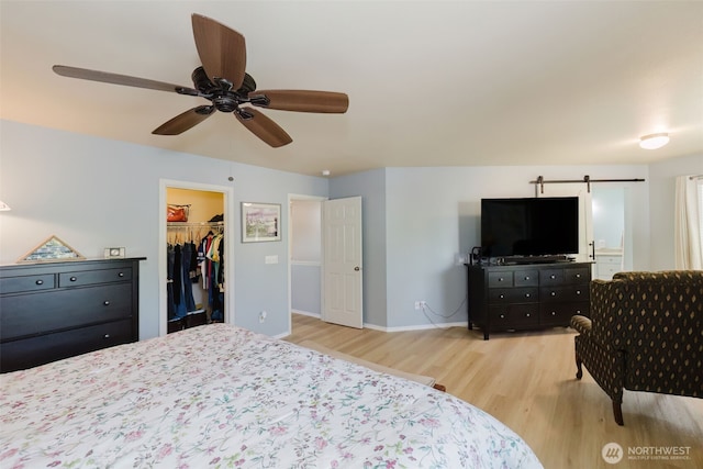 2760 SW Jabirin Way, Port Orchard, WA 98367 - bedroom with wood finished floors, a barn door, a spacious closet, baseboards, and ceiling fan